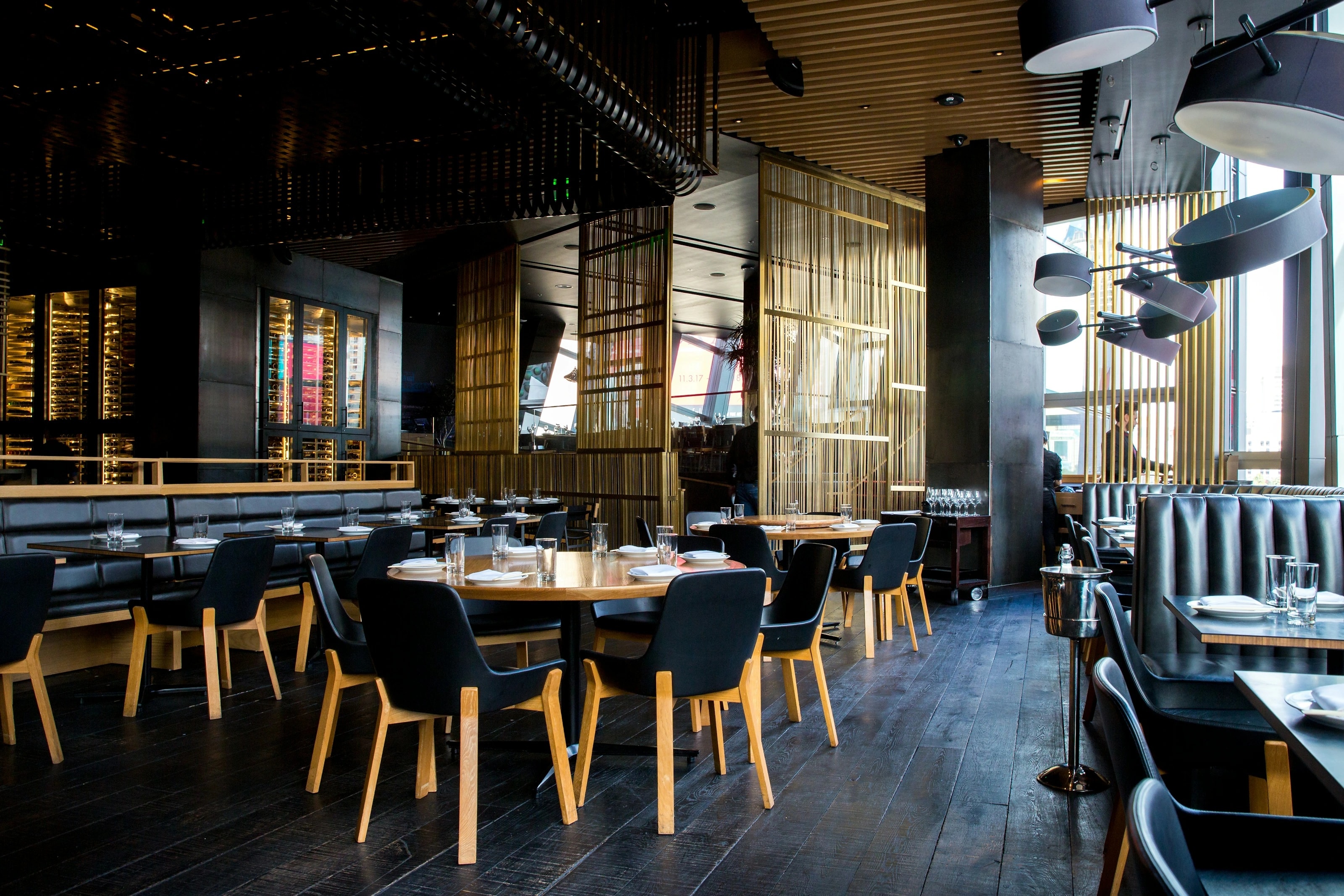 A contemporary dining room with laid tables, upholstered seating and warm brass details